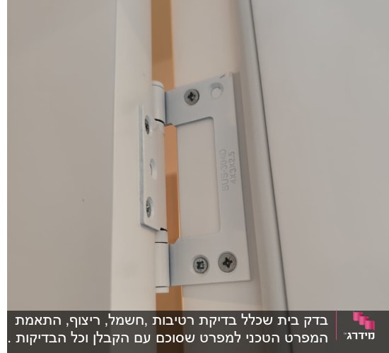 ציר מתכת מותקן על דלת לבנה